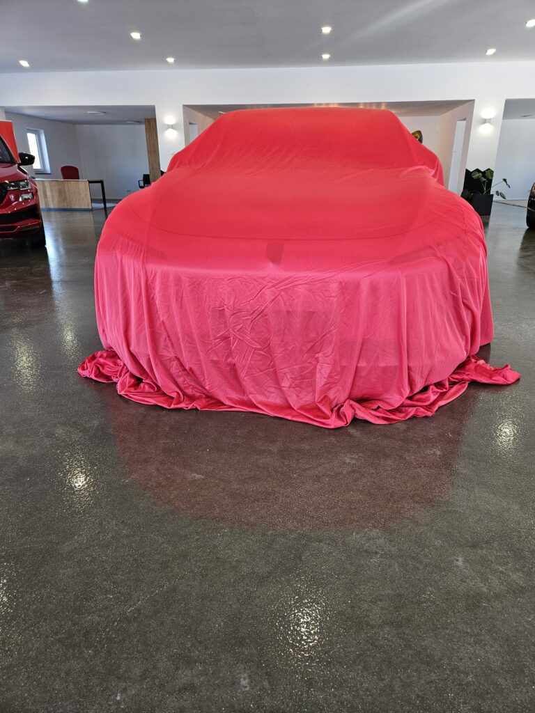 Fahrzeugpremiere bei STALLHOFER Mobility in Schönau – neues Fahrzeug unter Abdeckung im Showroom