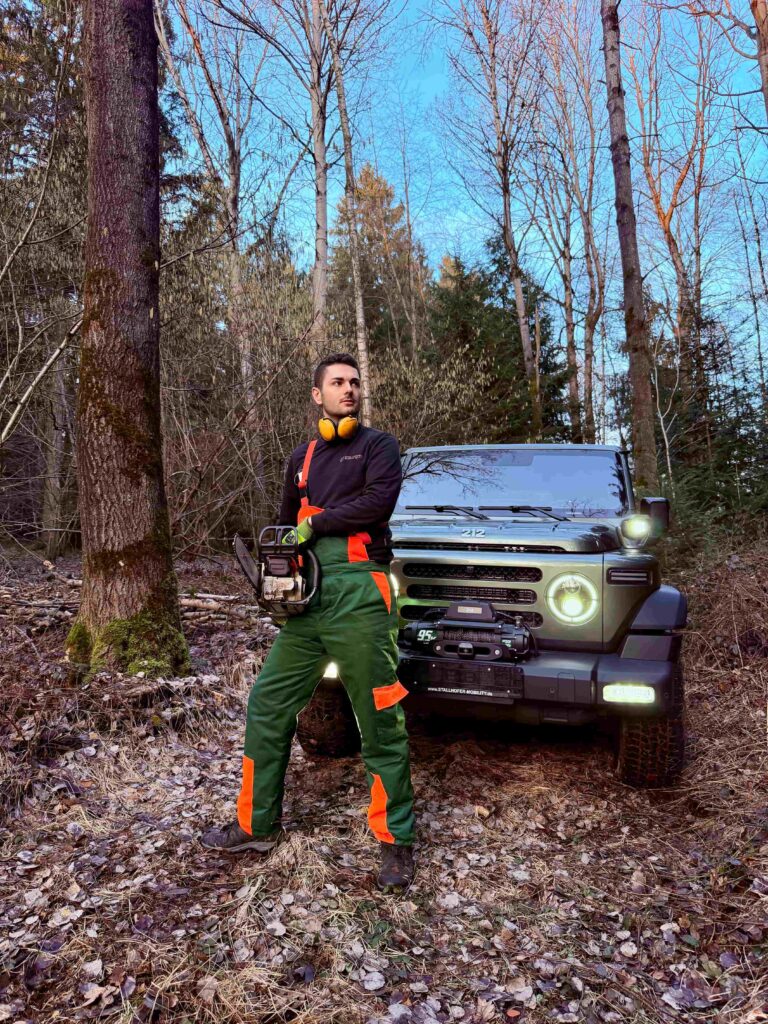 Waldarbeiter vor einem Geländewagen mit Motorsäge in Pfarrkirchen